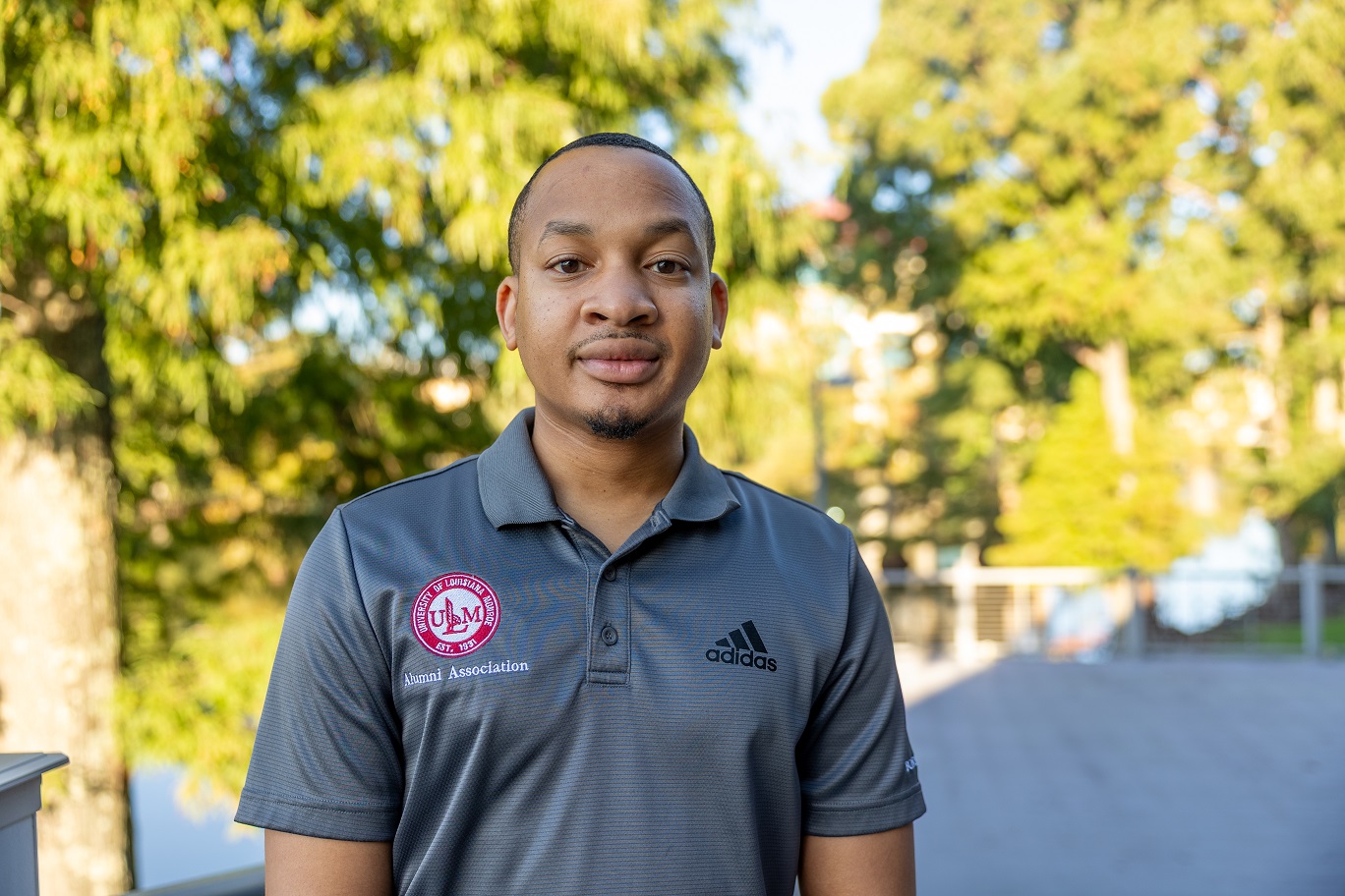 Portrait of Erick Burton, ULM Alumni Association Board Member, standing on campus near the bayou.