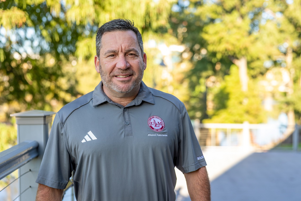 Portrait of Nicholas LeBas, ULM Alumni Association Board Member, standing on campus near the bayou.