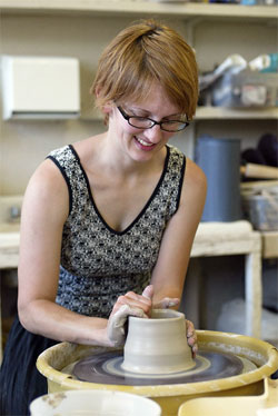 A ceramics student works with clay on a pottery wheel. 